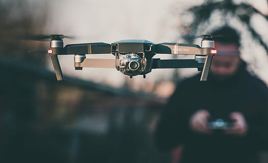 DJI Mavic Pro floating, black quadcopter drone with camera controlled by man in black jacket selective-focus photography HD wallpaper
