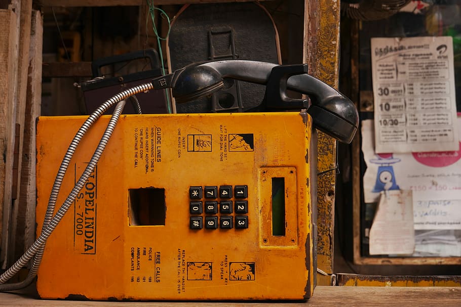 public telephone near window with papers, orange payphone near brown metal bar HD wallpaper