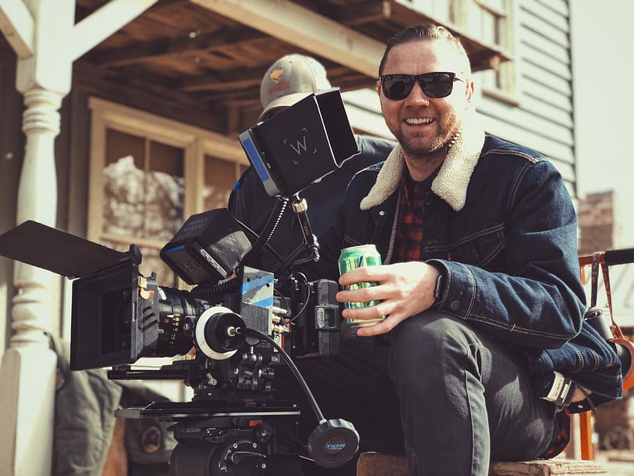 director holding green tin can, man wearing blue denim jacket holding video camera HD wallpaper