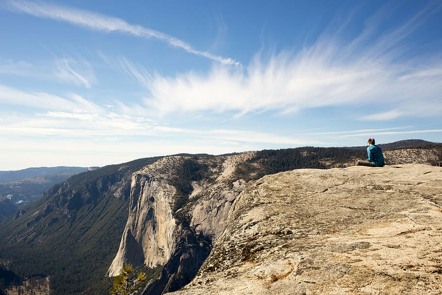 person sitting on cliff under blue skies, mountain, day, time HD wallpaper