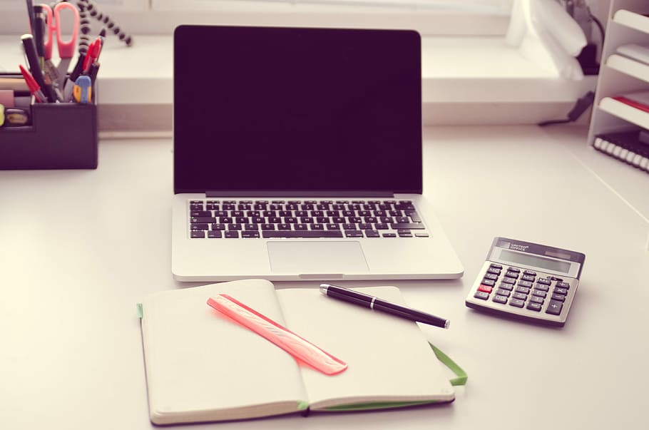 MacBook Pro beside gray and black calculator on white wooden table HD wallpaper
