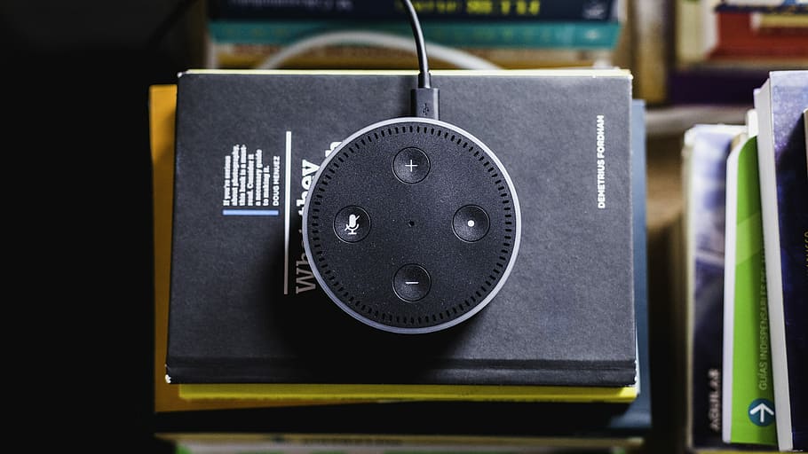 black Amazon Echo on black covered book, flat-lay photograph of 2nd generation black Amazon Echo Dot HD wallpaper