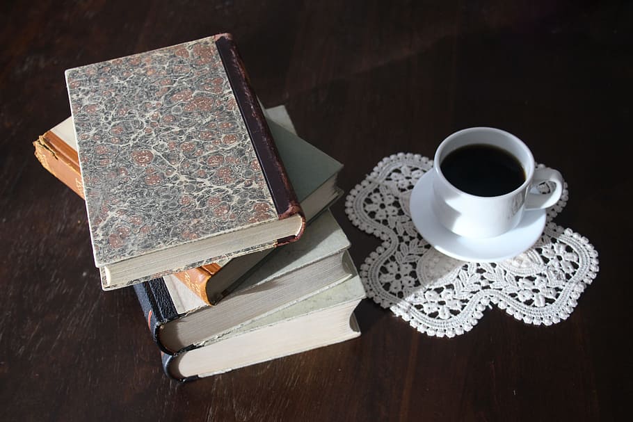 filled white cup on top of white saucer near four piled books HD wallpaper