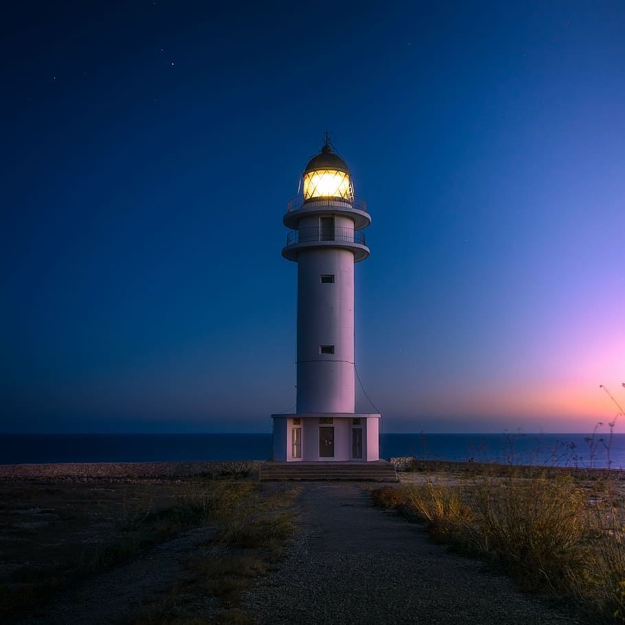 lighted lighthouse during nighttime, beach, cliff, coast, ocean HD wallpaper
