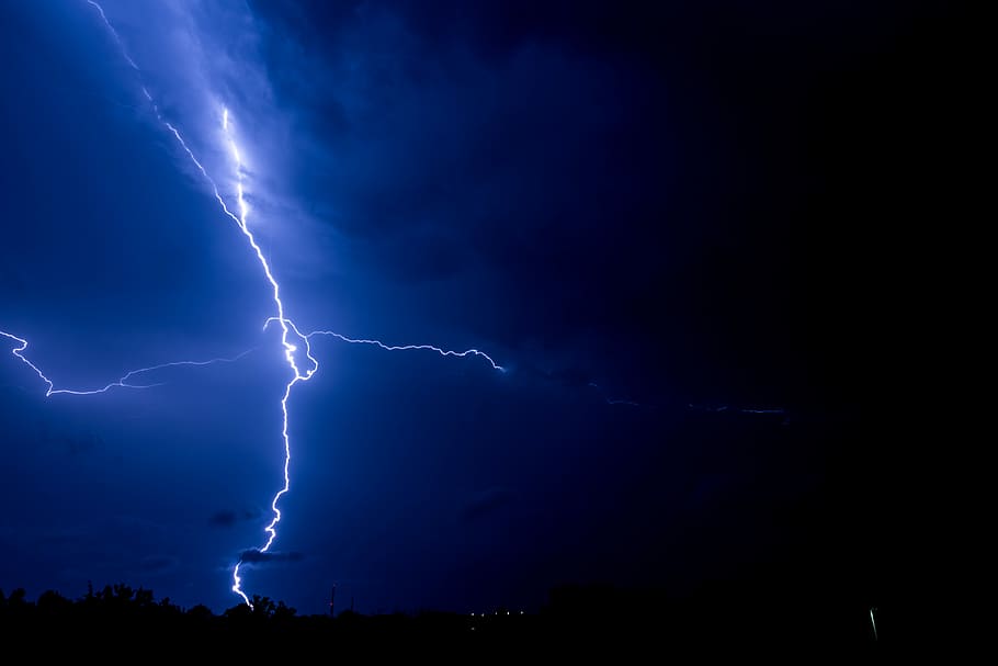 lightning bolts striking a body of land during night, blue lightning during night time