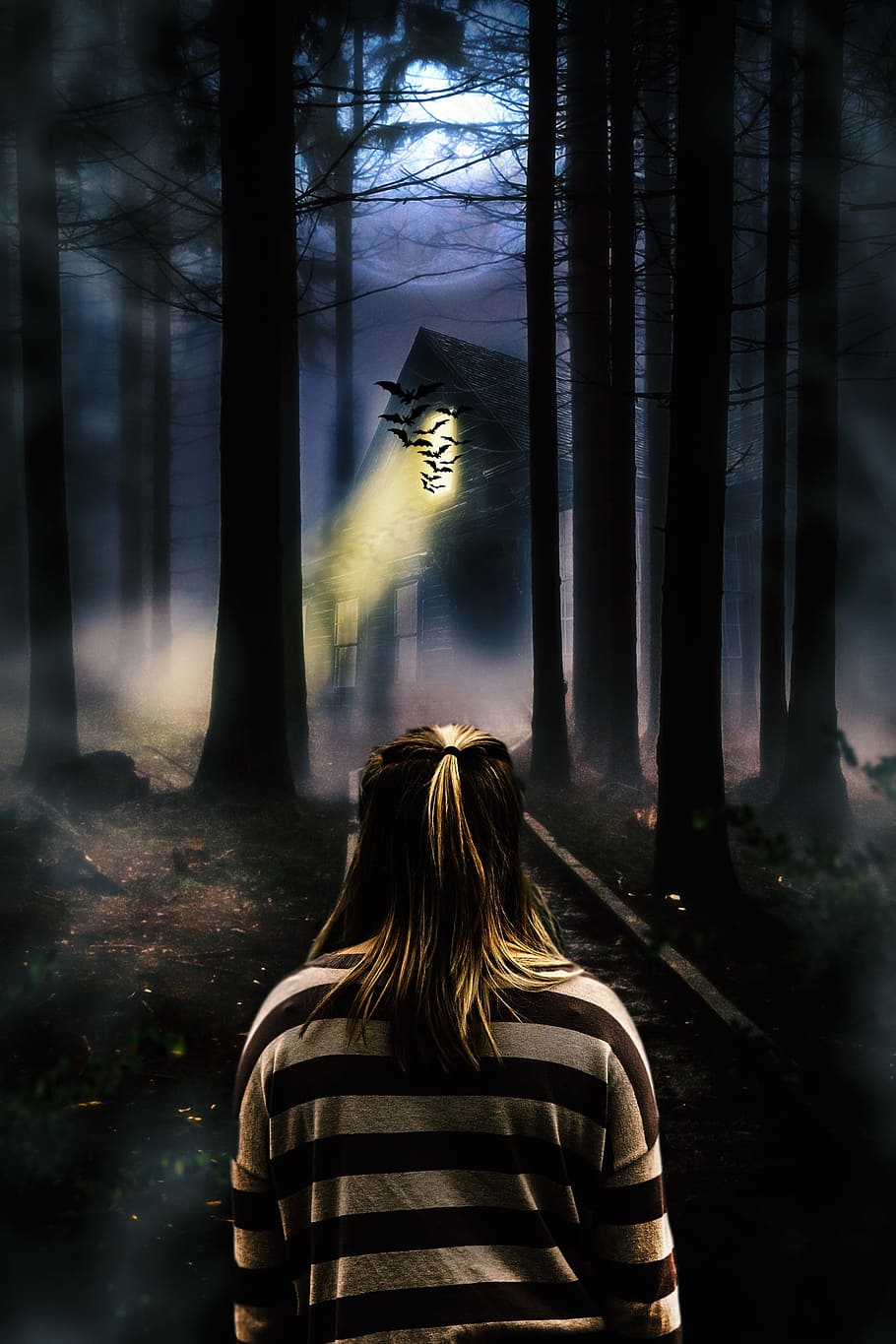 woman in beige and brown srtiped sweater standing inside woods during night time