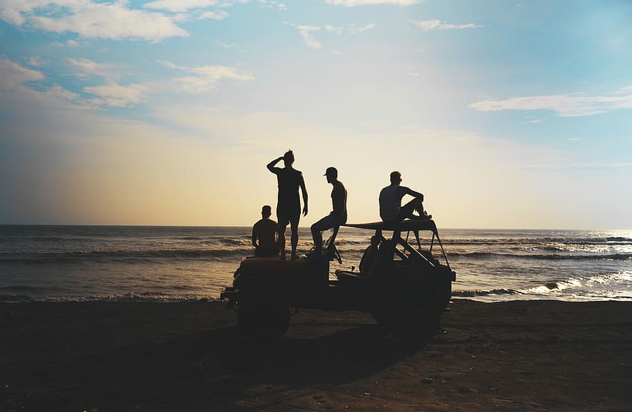 group of people riding SUV during daytime, people standing and sitting on vehicle at the beach during day HD wallpaper