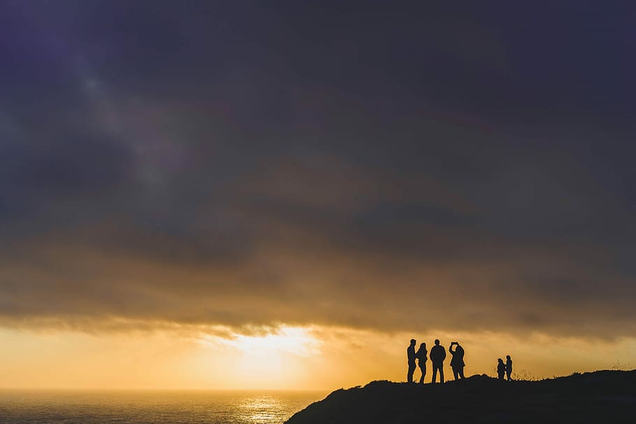 six people standing on mountain cliff at golden hour, silhouette group of people standing near body of water HD wallpaper