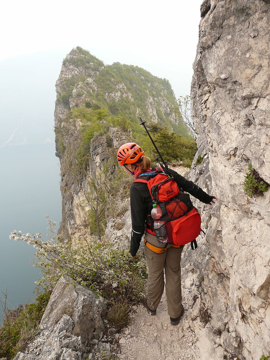 woman standing on mountain wearing red backpack, cima capi, via ferrata susatti