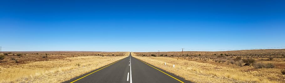 straight road between land mass under blue sky at daytime, africa