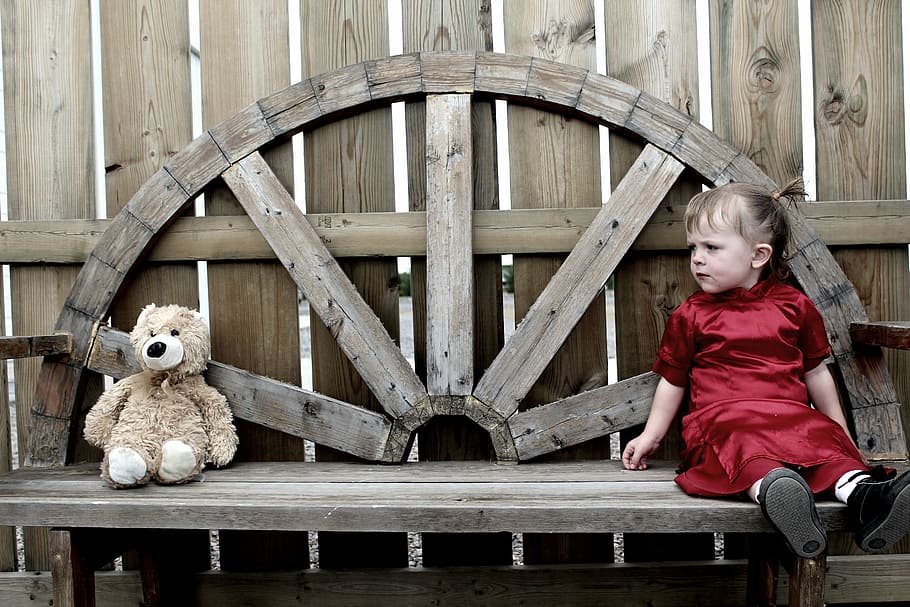 girl sitting on brown wooden bench while looking at brown bear plush toy, HD wallpaper