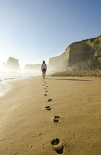 woman in white sleeveless top walking on gray sand beach, footsteps HD wallpaper