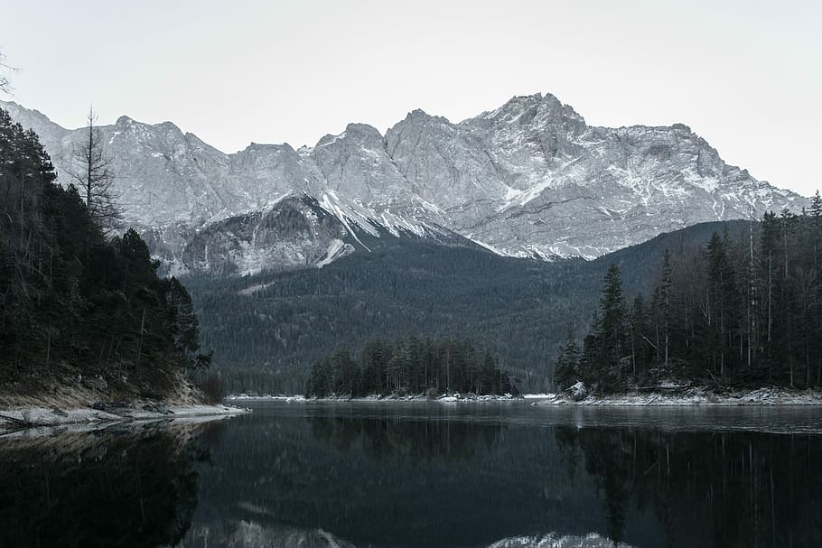 rocky mountain filled with snow near body of water under white sky, body of water near rocky mountain HD wallpaper
