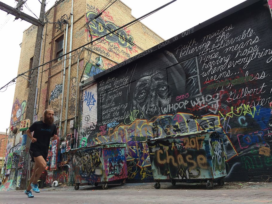 man in black shirt running near wall with graffiti, man running near two dumpsters and wall with graffiti, HD wallpaper