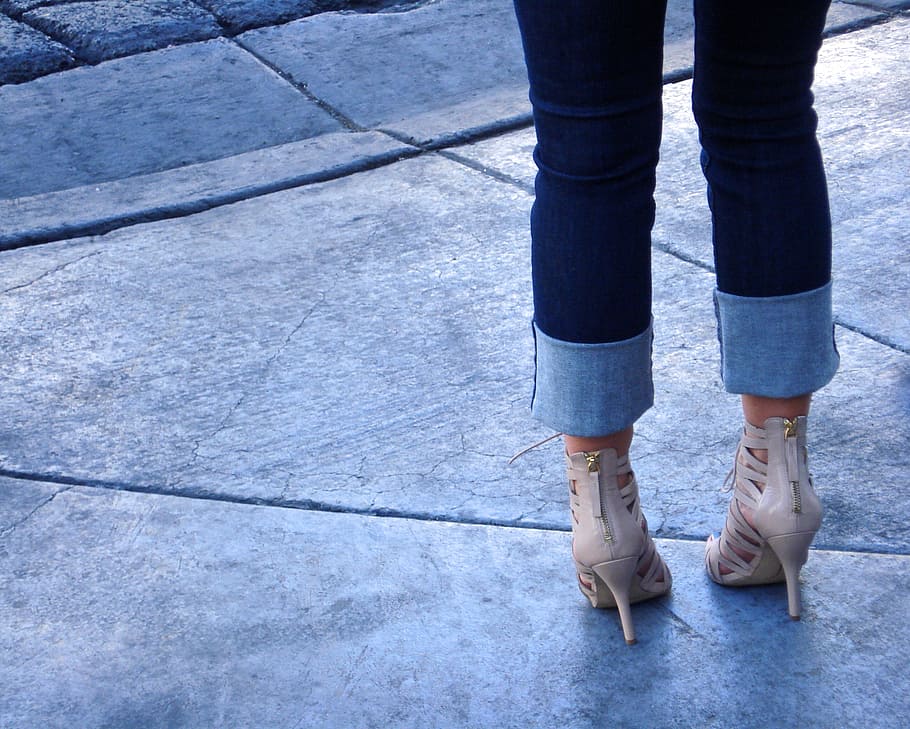 woman in blue denim jeans standing on gray concrete pavement