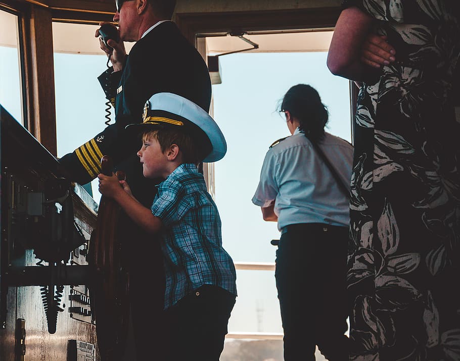 boy in plaid top wearing ship captain hat, man holding ship's wheel beside the captain HD wallpaper