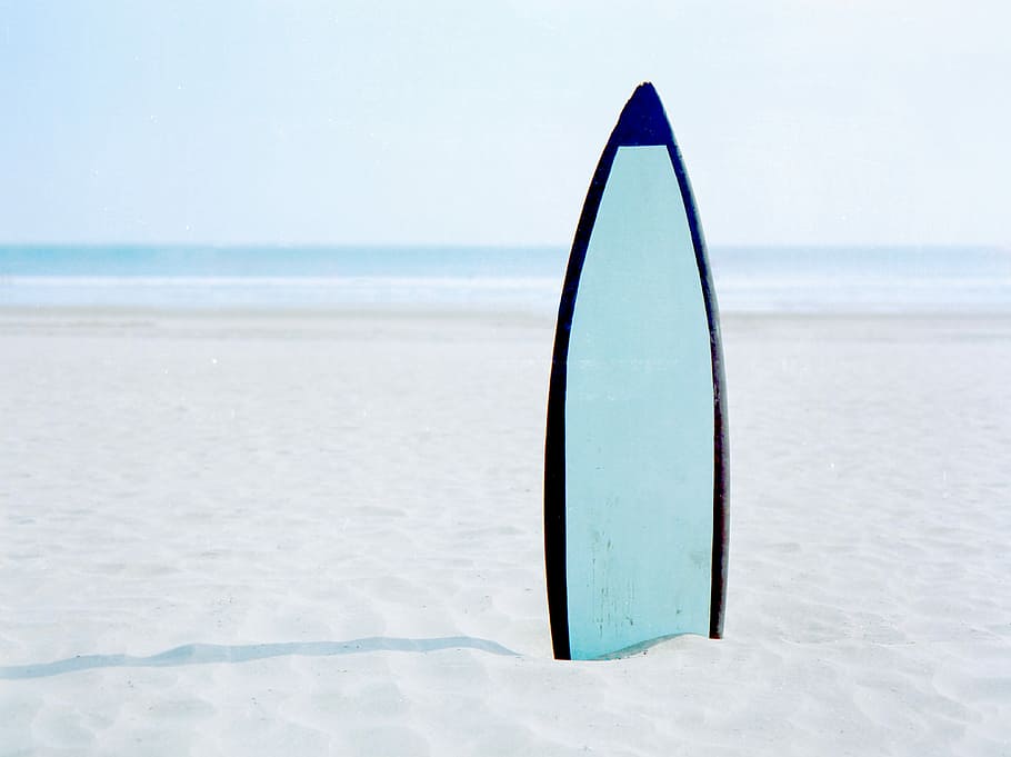 surfboard on seashore, close up photo of blue surfboard on seashore