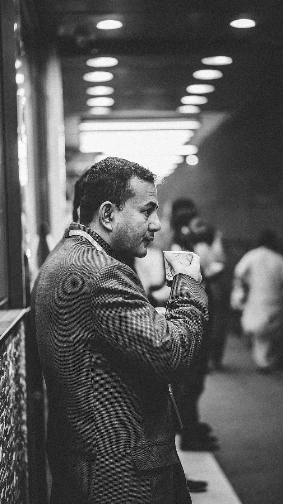 grayscale photo of man drinking on plastic cup, grayscale and selective focus photography of man holding paper cup