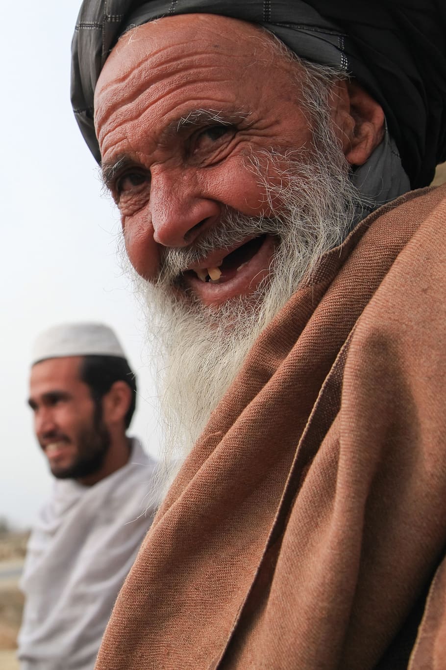 smiling man beside man wearing white headwear closeup photo, old