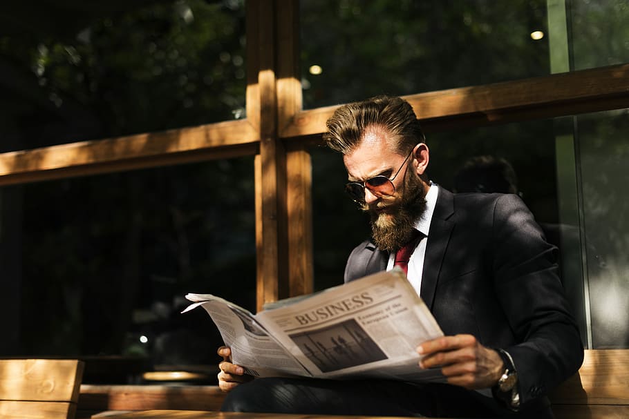 Businessman with a paper, man reading business newspaper while sitting on bench