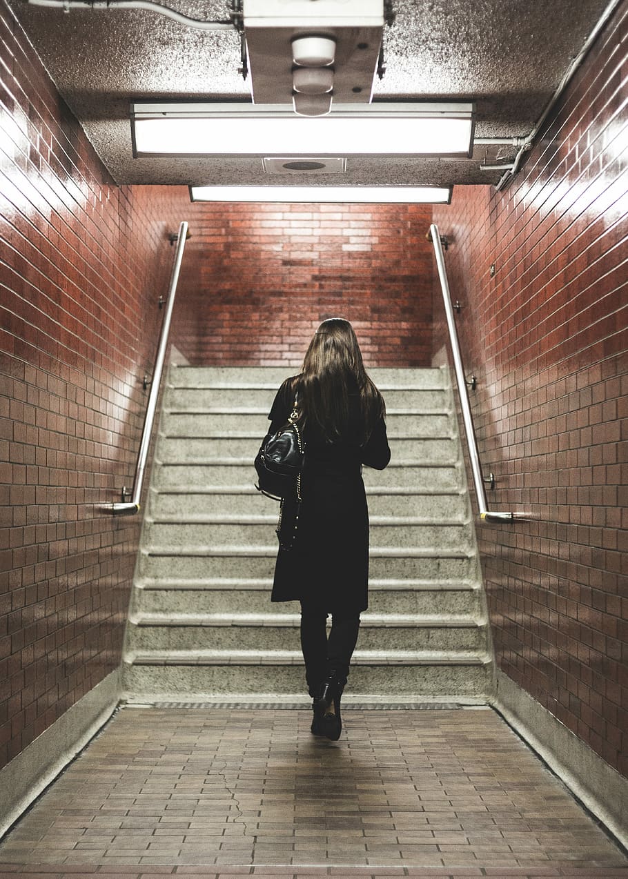 woman walking near staircase, woman walking on brown ceramic floor tiles