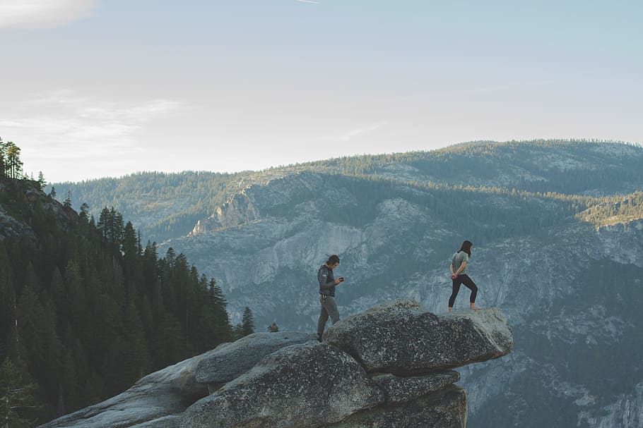 two men on mountain edge, two persons on gray mountain boulder HD wallpaper
