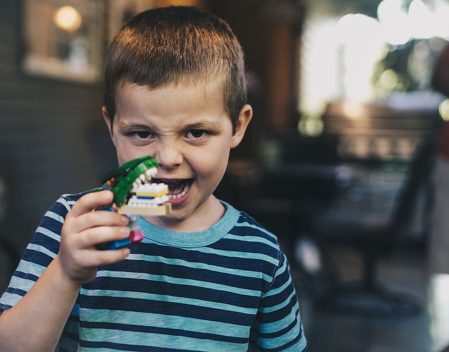 boy wearing teal and black striped t-shirt holding toy, shallow focus photography of a boy holding a mouthpiece toy, HD wallpaper