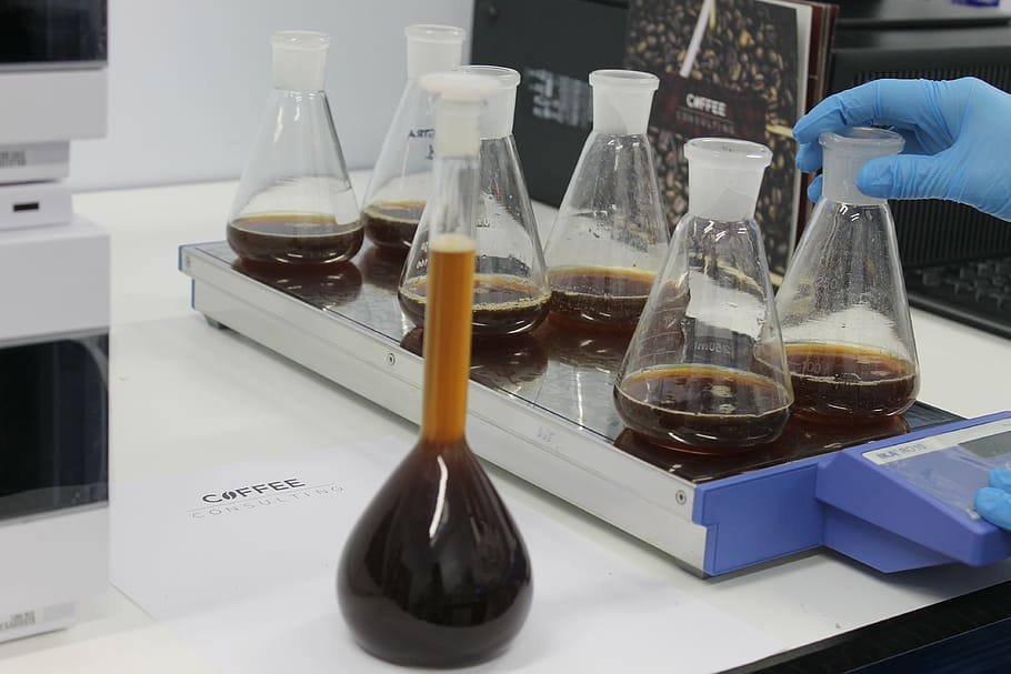 several clear glass Erlenmeyer's flasks with brown fluid on white table HD wallpaper