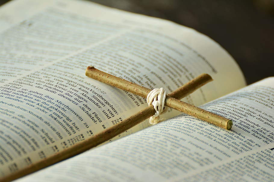 brown twig cross in between book pages, bible, easter, good friday