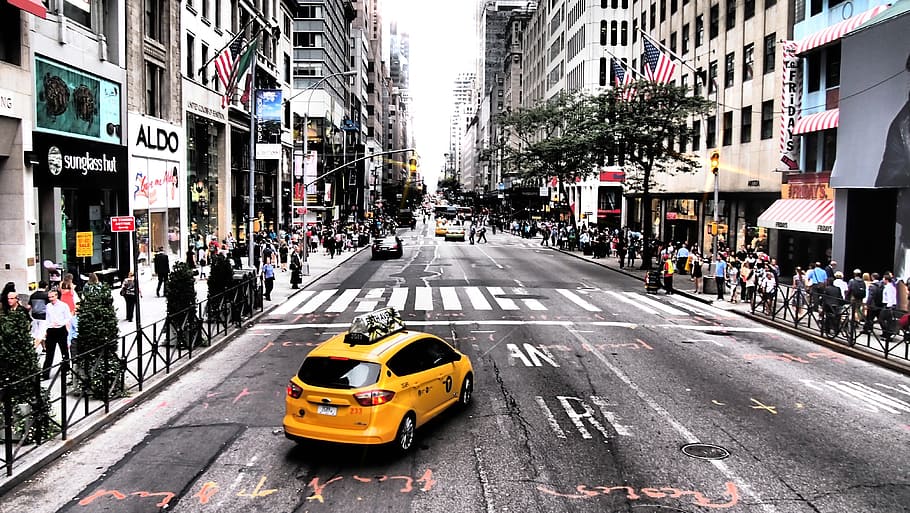 photo of a yellow cab on road between high-rise buildings, taxi