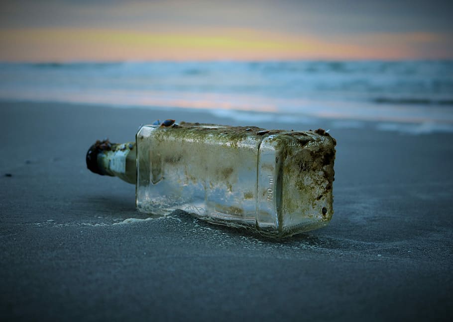 selective focus photography of bottle drifted on shore, clear glass bottle on sand near seashore HD wallpaper