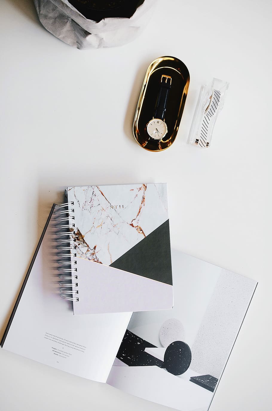 top view photography of round silver-colored analog watch with black leather strap on case near white covered notebook, round silver-colored analog watch on grey steel case HD wallpaper