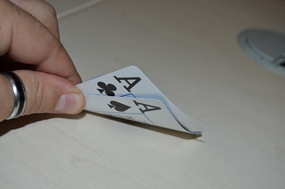 person holding two Ace of Clubs and Spades playing cards, poker