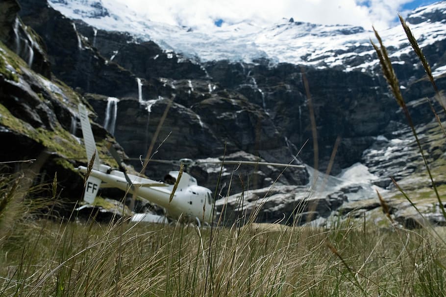 white helicopter near the snow capped mountains, grass field overlooking snow covered mountain HD wallpaper