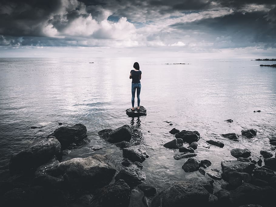woman standing on rock surrounded with body of water, woman in black t-shirt standing on gray rock watching ocean view during daytime, HD wallpaper