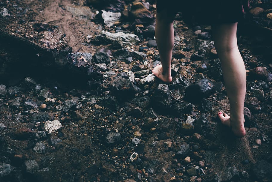 person walking on rocky grounds, person's feet walking on rocks