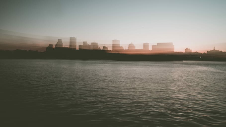 landscape photography of cityscape, silhouette of city between sky and body of water HD wallpaper