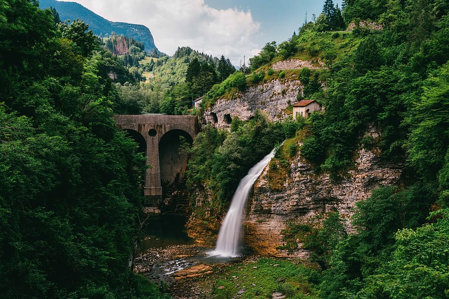 water fountain near concrete bridge and surrounded of trees at daytime, waterfall beside concrete bridge HD wallpaper