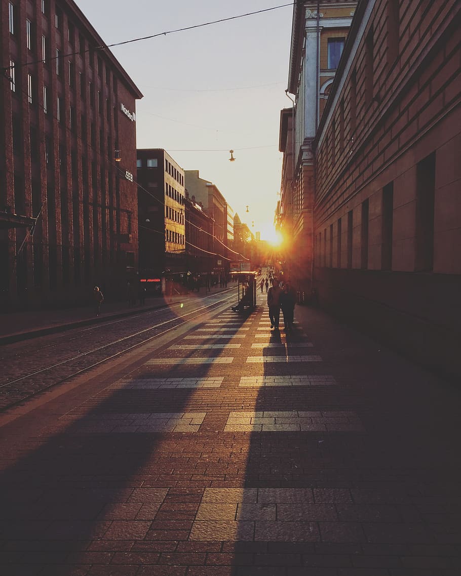 two person walking between concrete buildings, photography of street during sunset HD wallpaper