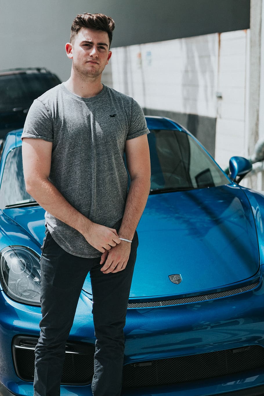 man wearing grey t-shirt and black pants standing in front of blue Porsche vehcile, men's gray crew-neck shirt HD wallpaper