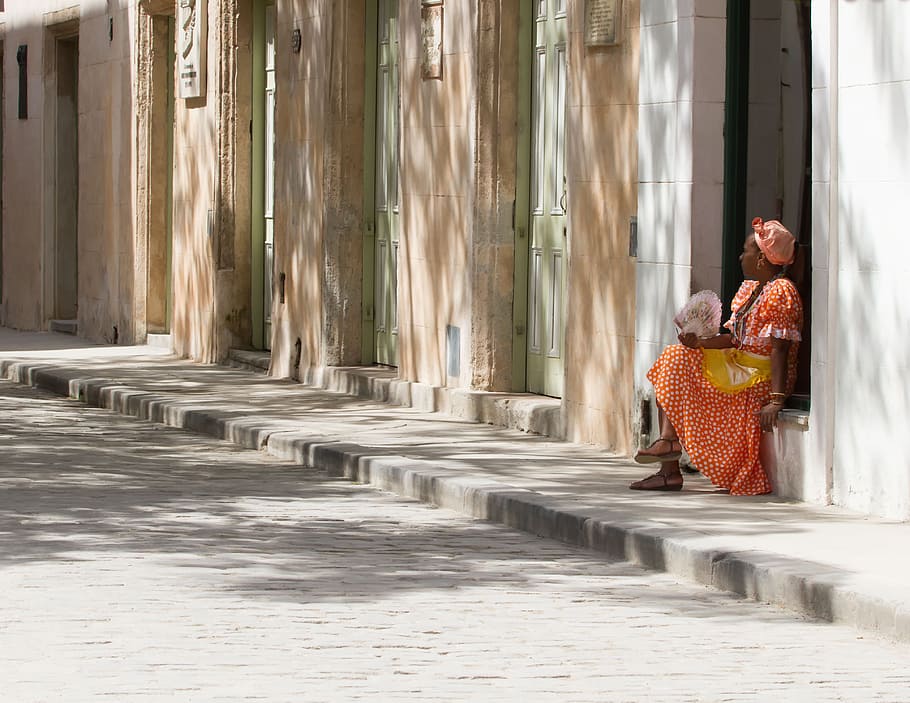 woman wearing red dress sitting on gray concrete wall, Havana, Cuba