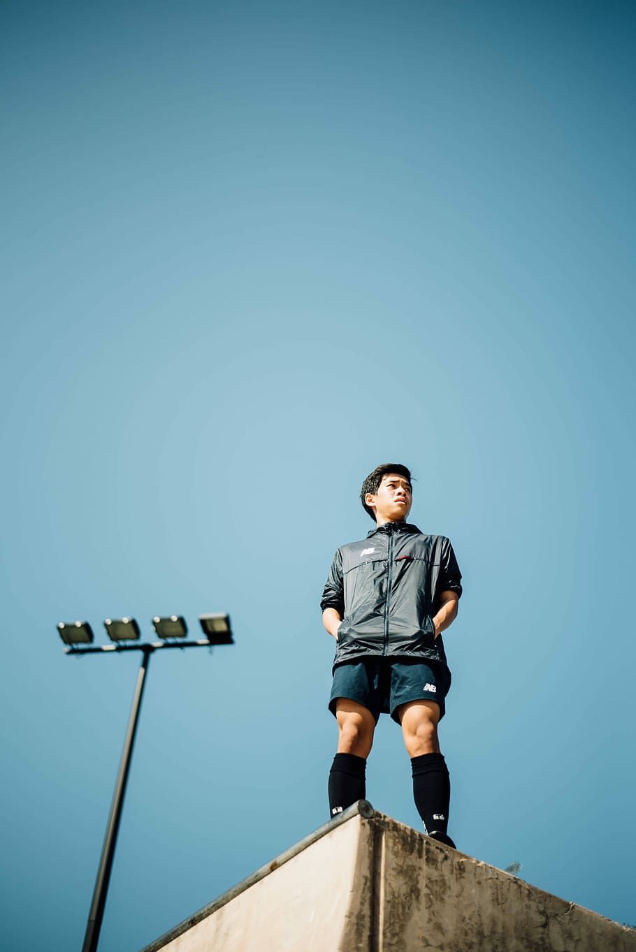 man in black zip-up shirt and blue shirts standing on top of building under clear blue sky during daytime HD wallpaper