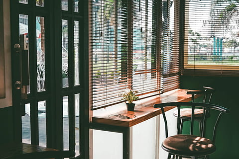 Cozy coffee shop corner, two brown padded bar stools near end table and window blinds HD wallpaper