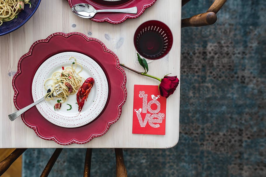 Fancy dinner with seafood pasta, crayfish and red wine by the table decorated with roses HD wallpaper