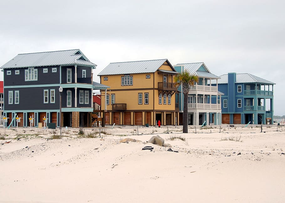 black, brown, and blue painted houses on brown sand under blue sky during daytime HD wallpaper