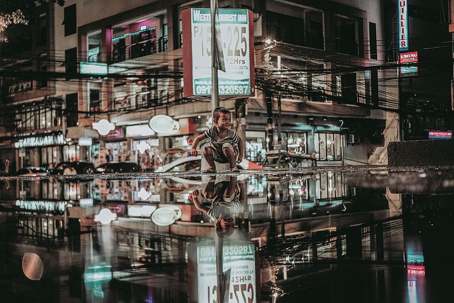 reflection photography of boy sitting beside pole near restaurant, edited photo of boy with road reflection, HD wallpaper