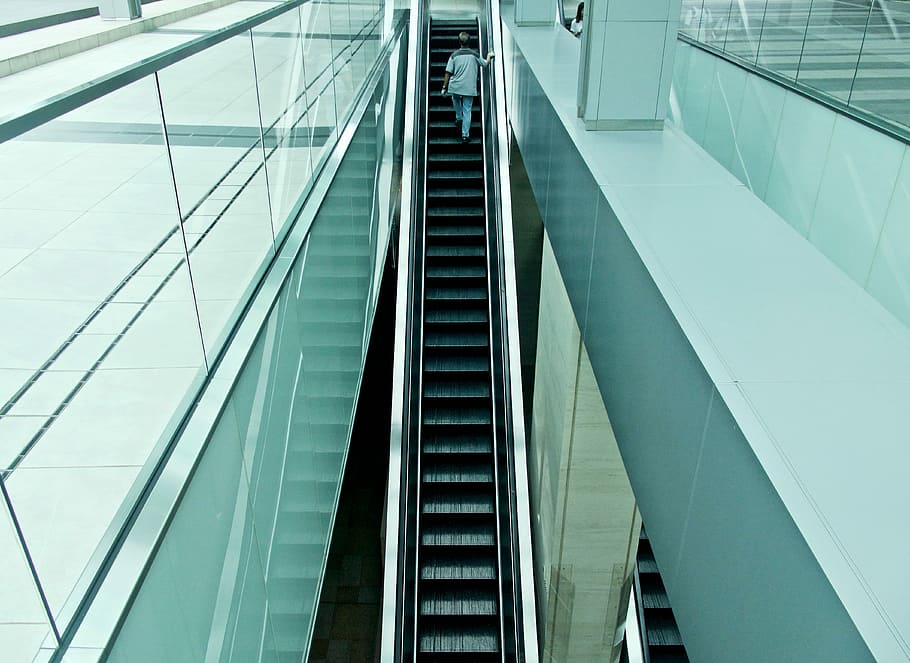 man riding on escalator, person on escalator inside white painted building HD wallpaper