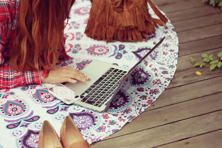 woman holding laptop computer on white and pink floor mat near fringe bag and shoes HD wallpaper