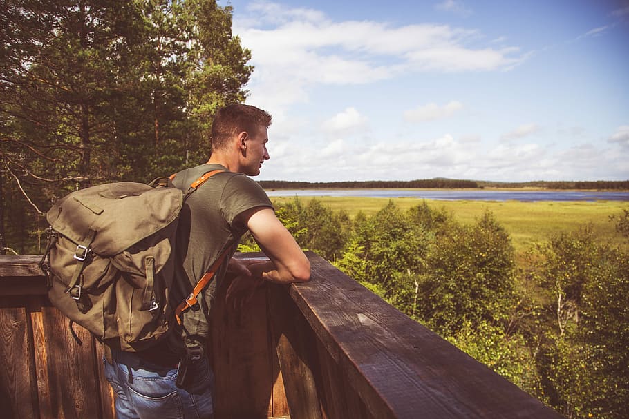 woman leaning on wooden patio surrounded by grasslands and trees, man standing beside brown wooden railing HD wallpaper