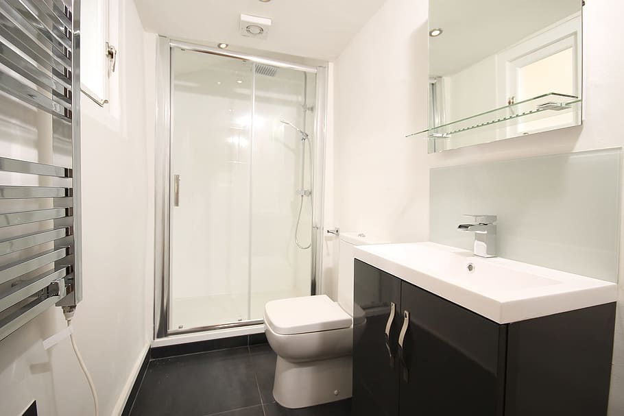 white ceramic toilet bowl near black and white vanity combo, shower